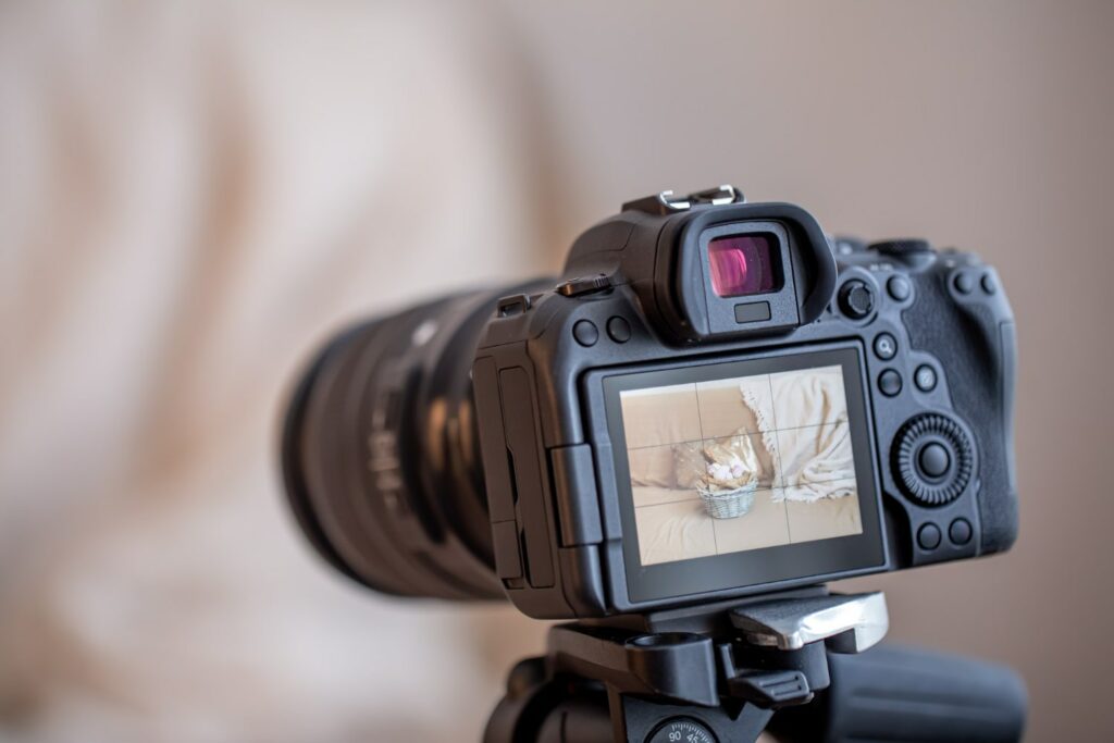 Imagem de uma câmera digital profissional sobre um tripé, focando um objeto decorativo em um cesto em um ambiente interno. Excelente para ilustrar artigos sobre a faculdade de fotografia.